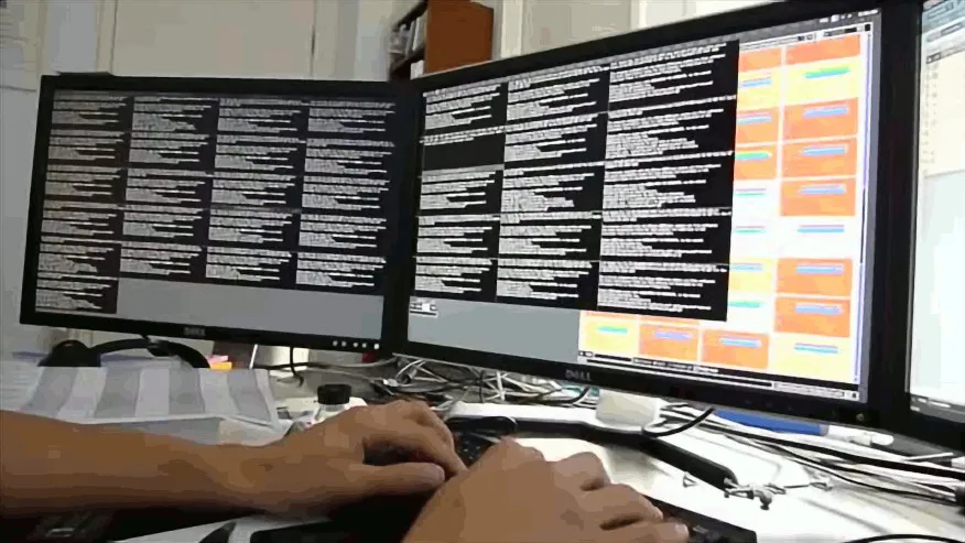 Hands typing on a keyboard below three screens displaying 36 small ssh terminals
